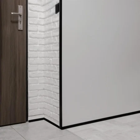 Black PVC Corner Protector Fitted to an External Wall Corner, 1m Black PVC wall corner protector trim installed on an external wall corner in a hallway