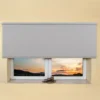 Light grey light filtering roller blind fitted above a recessed window, sunset view