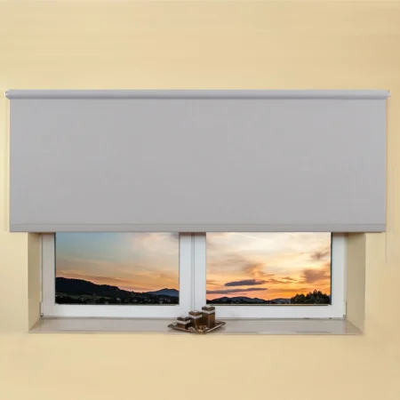 Light grey light filtering roller blind fitted above a recessed window, sunset view