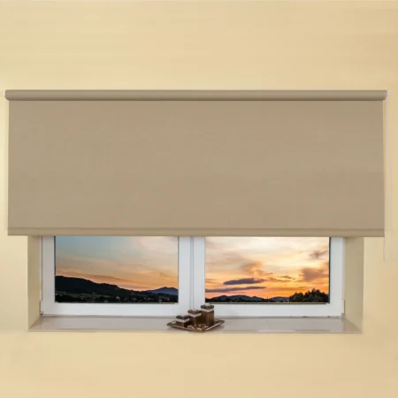 Beige light filtering roller blind fitted above a recessed window, with a sunset view