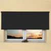 Black light filtering roller blind fitted above a recessed window, with a sunset view