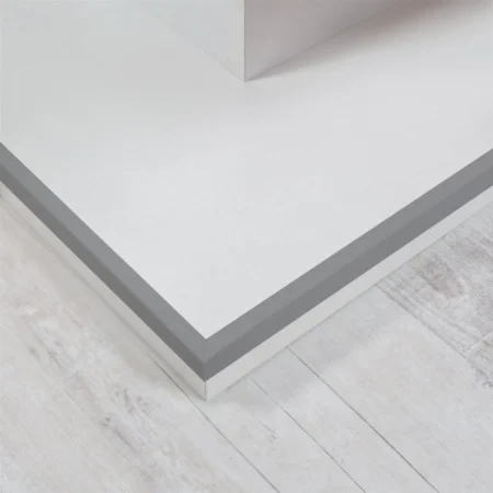 Gray PVC Angle Trim on a Plinth Edge, 1m Corner Protector Gray PVC angle trim installed horizontally on the outer edge of a raised white plinth